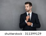 Perfect to the last detail. Handsome young businessman adjusting his sleeves while standing against grey background