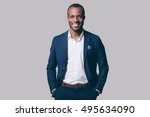 Young and handsome. Handsome young African man in smart casual jacket holding hands in pockets and smiling while standing against grey background