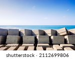 Small photo of Stone blocks on a seawall of a port breakwater on the Atlantic coast on a sunny day.