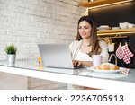 Smiling young woman having breakfast  while working on laptop at home. Work from home concept.