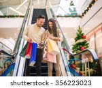 Romantic Christmas shopping.Sale, technology and people concept - happy young couple with shopping bags.Image taken inside a shopping mall.Selective focus