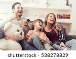 Young family watching TV together at home and having fun together.