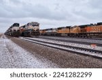 Small photo of Gillette, Wyoming - January 23, 2021: Four rows of train tracks with train engines on a cloudy winter day near Gillette, Wyoming.