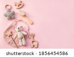 Bib and wooden toys. Set of baby stuff and accessories for girl on pastel pink background. Baby shower concept. Fashion newborn. Flat lay, top view