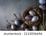 Small photo of Easter card with a copy of the place for the text. Purple, blue and golden eggs with lavender on a dark background. The purple hue trend of 2022 is very relevant. Natural dye karkade tea. Top view.