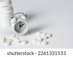 A tube of pills and an alarm clock. The time on the clock is 2 am. Insomnia and recovery of sleep mode. Taking pills by the hour.