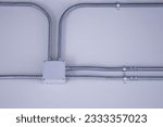 Small photo of Electrical junction box and conduits on the wall. Home electrical system with electrical junction box with galvanized conduit fittings mounted on a white wall indoors. selective focus