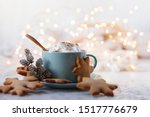 Small photo of Hot winter drink: chocolate with whipped cream in blue mug. Christmas time. Cozy home atmosphere, white background. Homemade gingerbread cookies, cones and lights as decor. Holiday mood in the air!