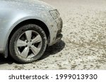 Small photo of The car is dirty by accident. Cement squirted at the car and it's dirty. The wheel and bumper of the car in the construction mud. Splashes of cement on the surface of the car and asphalt.