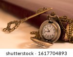 A pocket watch and a key resting against an old book. a concept of time and freedom.