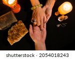 Small photo of Detail of a woman's hands reading the lines of a man's hand in a palmistry session. Concept of a hand lines divination session. View from above.