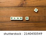 Small photo of The phrase PLAN B is made up of lettered parts, the letter A is set aside. Concept of planning for the future, resilience and constancy. Background of wooden boards and copy space.