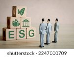 ESG ,environmental, social, and corporate governance concept.,A group of business man focus on wooden cubes with ESG word and icon showcasing a commitment to ethical and sustainable business.