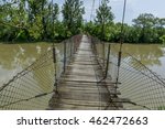 Old steel cable and wooden  footbridge across river. Wooden suspension bridge.