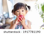 Small photo of Portrait​ image​ of​ 2-3 yeas​ old​ of​ baby.​ Happy​ Asian child girl eating and biting an red apple. Enjoy eating moment. Healthy food and kid concept.​