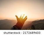 Young man hand reaching for the mountains during sunset and beautiful landscape