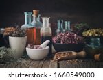 Bottles of healthy tincture or infusion, mortar and bowls of medicinal herbs on wooden table. Herbal medicine.