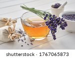 Small photo of Cup of healthy lavender tea and lavender flowers. Mortars of dry lavender and sachets on background. Alternative medicine.