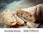 Fresh bread slice and cutting knife on rustic table