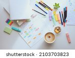 Small photo of Top view of the white work desk with colourful stationery. Student's schedule for the week. Planning a working week with coffee and snacks. layout.