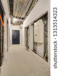 Small photo of Hall before leveling, finishing, painting and plastering. Empty corridor. Construction stage of residential monolithic house. Distribution board (panelboard, breaker panel). Heating pipes on floor