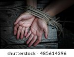 Woman's hands tied with rope lying on a wooden board.