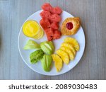 Watermelon in heart shape, pineapple and guava fruit, glass of pineapple juice and danish on white plate. Healthy breakfast concept. Valentine or wedding day morning. Top view flat lay