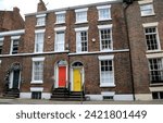 Small photo of Liverpool, United Kingdom - June 19, 2023: A pair of brightly colored doors break up the monotony of an old brick building in the heart of historic Liverpool.