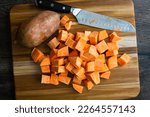 Small photo of Peeled Sweet Potatoes Chopped Into Large Cubes: Prepped sweet potato chunks on a wooden cutting board