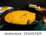 Small photo of Buttermilk Cornbread Baked Cut Into Pieces in a Cast-Iron Skillet: Freshly made Southern cornbread in a frying pan with butter and honey on the side