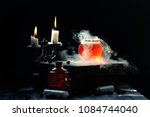 Small photo of Magic and wizardry concept. Set of sorcery book, magic potions and candles on table. Health potion with vapor streaming from bottle. Alchemy concept.