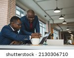 Two dark-skinned partners of an African American businessman in a meeting work on a laptop in the office. Affordable private courses and distance learning. New opportunities online