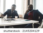 Small photo of Two dark-skinned partners of an African American businessman in a meeting work on a laptop in the office. Affordable private courses and distance learning. New opportunities online