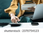 Small photo of woman working on laptop and accounting financial report, accountant using calculator to calculate tax refund at office.