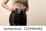 Small photo of Thigh bag with different brushes on faceless professional makeup artist. Unrecognizable make-up artist with belt bag with tassels or makeup brushes over beige background