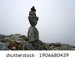  Stones stacked on top of each other in a pillar. Against the white cloud backdrop.Stone piles on top of each other, Slovakia. High Tatras national park                            