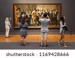 Small photo of Amsterdam, Netherlands - May 2018: Tourists look at a painting of "The Meagre Company" (by Frans Hals and Pieter Codde) displayed at the Rijksmuseum