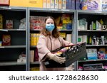 Small photo of ROTHERHAM, UK - MAY 6, 2020: A volunteer at a Trussell Trust food bank wears gloves and face mask PPE in the coronovirus pandemic whilst packing a client parcel
