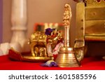 Small photo of Stock photo of a brass pooja room bell with temple deity in background. It drowns inauspicious noises and brings spiritual vibrations to the prayer ceremony.It produces strains of om. Selective focus.