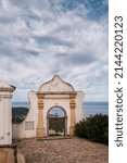Small photo of Cemetery entrance at Sant'Antonino in the Balagne region of Corsica with the Mediterranean sea in the distance