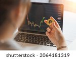 Businesswoman, investor, trader hold Bitcoin Cryptocurrency, using computer laptop with graph chart, trading stock market, investing Bitcoin cryptocurrency at home. Investment and technology concept.