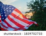 Veterans Day Flag Of The United States Of America. American flag flying on the background of the setting sun in nature.