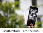 A person holding a printed black sign 