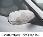 Ice-covered rear view side mirror. Dangerous conditions during winter storm.