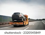 Tow truck with broken car on country road. Tow truck transporting car on the highway. Car service transportation concept.
