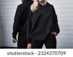 Stylish Hoodie Mockup. Fashionable Autumn Streetwear for Young Couples. Woman and man wear black hoodies without a logo. No logo basic sportswear. Long sleeve sweatshirt mockup