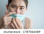 Small photo of Asian woman worry about acne occur on her face after wearing mask for long time during covid-19 pandemic. Wearing mask for prolonged periods can damage the skin.