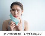 Small photo of Asian woman worry about acne occur on her face after wearing mask for long time during covid-19 pandemic. Wearing mask for prolonged periods can damage the skin.