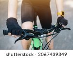 Cropped shot of cyclist hands wearing glove and holding a handlebars for control a bike. A bicycle handlebar is the steering control for bicycles.