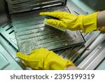 Small photo of Housekeeping put stained filters of cooker hood in sink before cleaning it by sponge. Clean your filters every two to three months, depending on your cooking habits.